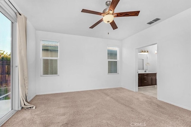 unfurnished bedroom featuring ensuite bath, ceiling fan, and light carpet