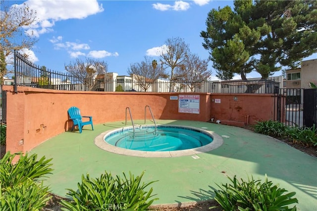 view of swimming pool featuring fence and a hot tub