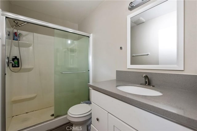 bathroom with a stall shower, vanity, and toilet