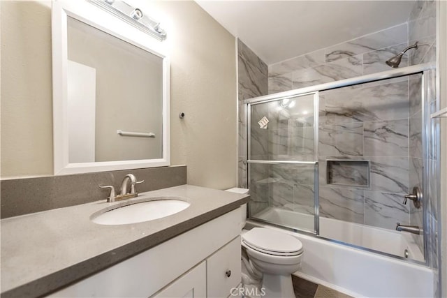 bathroom featuring toilet, shower / bath combination with glass door, and vanity