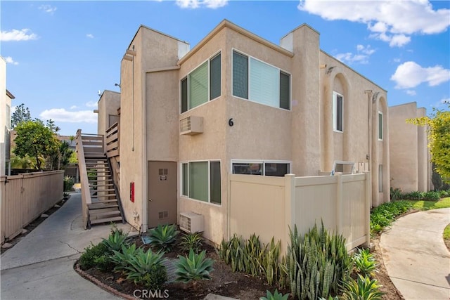 view of front of house featuring stairs, fence, and stucco siding