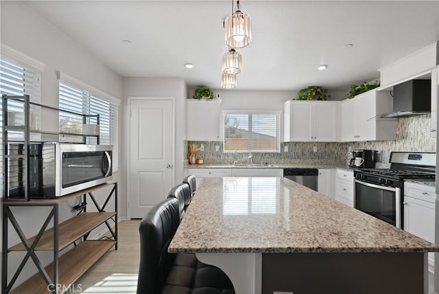 kitchen featuring white cabinets, a center island, stainless steel appliances, and hanging light fixtures