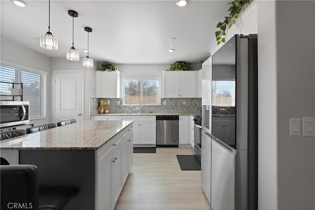 kitchen featuring white cabinets, plenty of natural light, a kitchen island, and stainless steel appliances