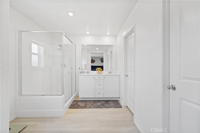 bathroom featuring wood-type flooring, vanity, and a shower with shower door