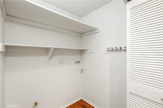 clothes washing area with hookup for a gas dryer, wood-type flooring, and a textured ceiling