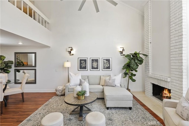 living room with a fireplace, crown molding, hardwood / wood-style floors, and a towering ceiling