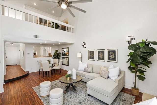 living room featuring a towering ceiling, hardwood / wood-style flooring, and ceiling fan