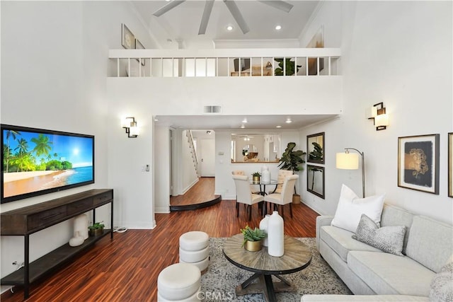 living room featuring a high ceiling, dark hardwood / wood-style flooring, ceiling fan, and crown molding