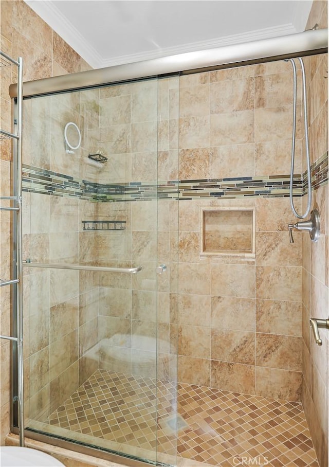 bathroom featuring toilet, a shower with door, and ornamental molding