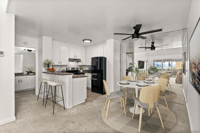 kitchen featuring electric stove, light colored carpet, white cabinets, and black fridge