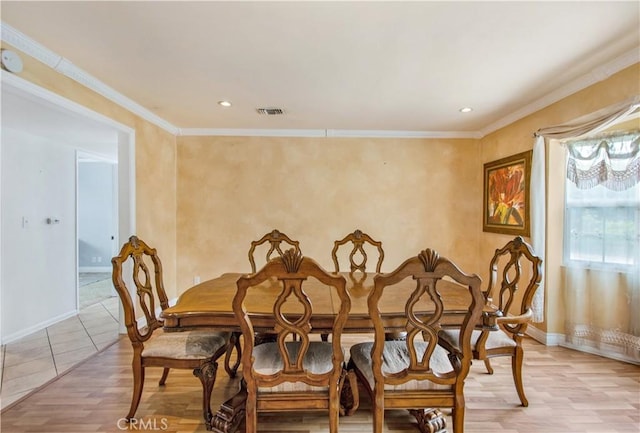 dining space with ornamental molding and light hardwood / wood-style flooring