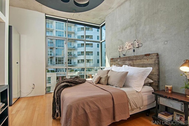 bedroom featuring multiple windows, ceiling fan, hardwood / wood-style floors, and a wall of windows