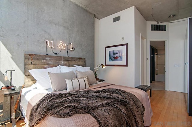 bedroom with light hardwood / wood-style flooring and a high ceiling