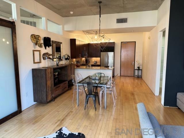 kitchen with stainless steel appliances, light hardwood / wood-style flooring, kitchen peninsula, a towering ceiling, and dark brown cabinets