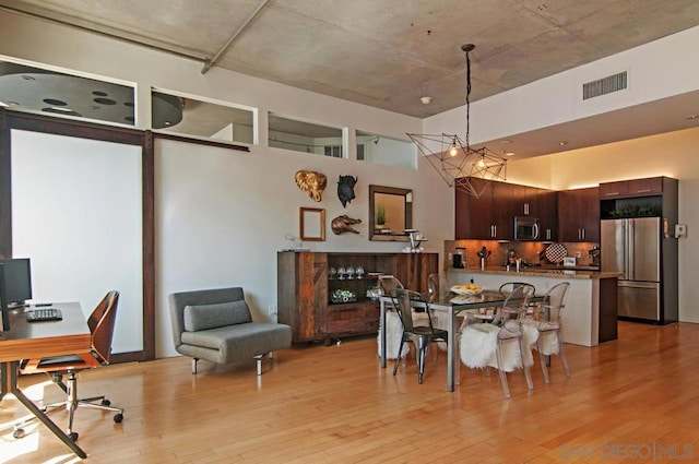 dining room with a high ceiling and light wood-type flooring