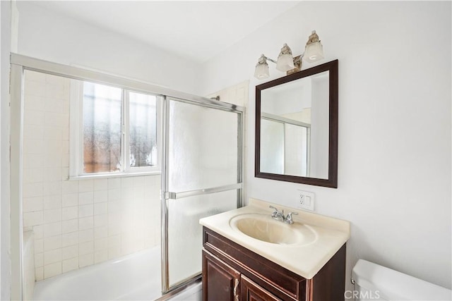 full bathroom featuring vanity, bath / shower combo with glass door, and toilet