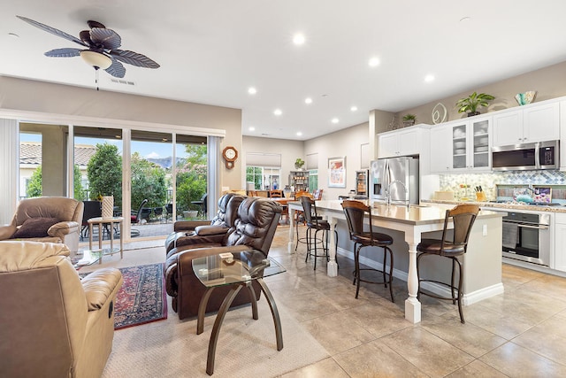 tiled living room with ceiling fan and sink