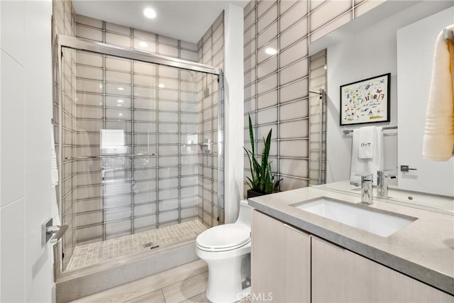 bathroom featuring a tile shower, vanity, and toilet