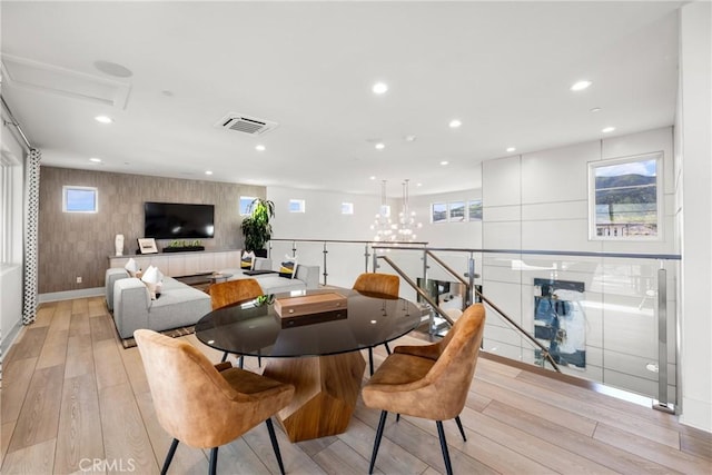 dining space featuring light hardwood / wood-style floors, a healthy amount of sunlight, and a chandelier