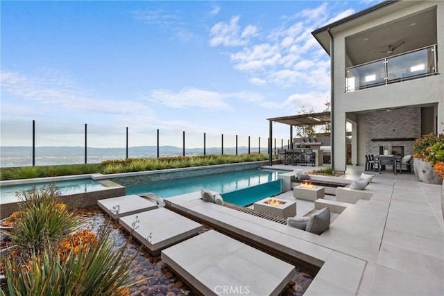 view of pool featuring a water view, ceiling fan, a patio, area for grilling, and an outdoor fire pit