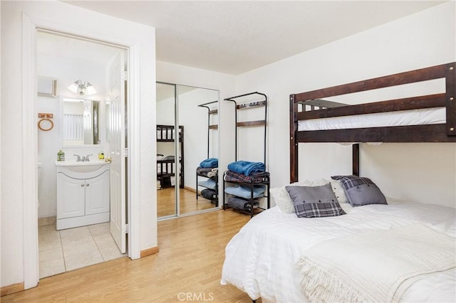 bedroom featuring hardwood / wood-style floors, ensuite bath, and a closet