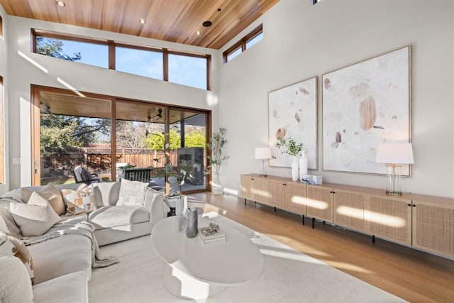 living room with a high ceiling, wooden ceiling, and light hardwood / wood-style floors