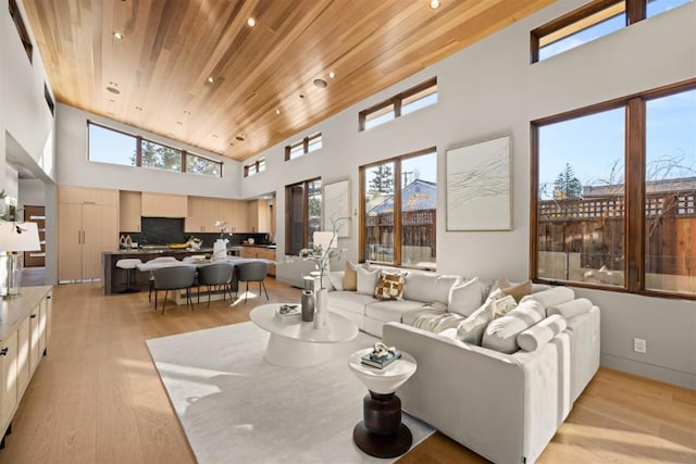 living room with a towering ceiling, wooden ceiling, and light hardwood / wood-style floors