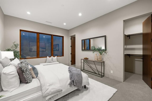 bedroom with a walk in closet, light colored carpet, and a closet