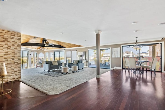 living room featuring ceiling fan with notable chandelier, lofted ceiling, dark wood-type flooring, and a wealth of natural light