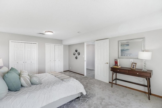 bedroom with light carpet and two closets