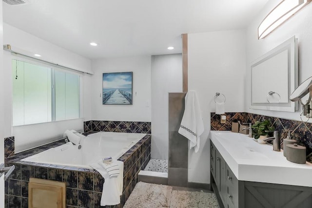 bathroom with vanity and a relaxing tiled tub