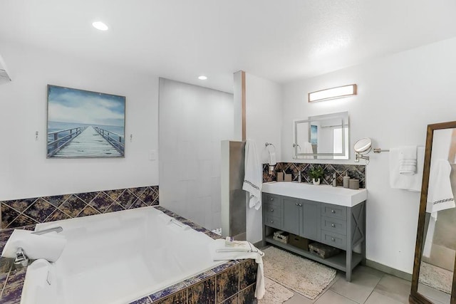 bathroom with a relaxing tiled tub, tile patterned floors, and vanity