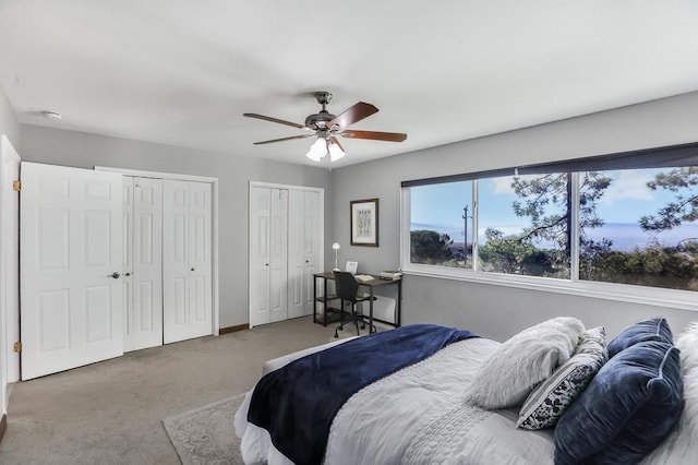 carpeted bedroom featuring ceiling fan and two closets