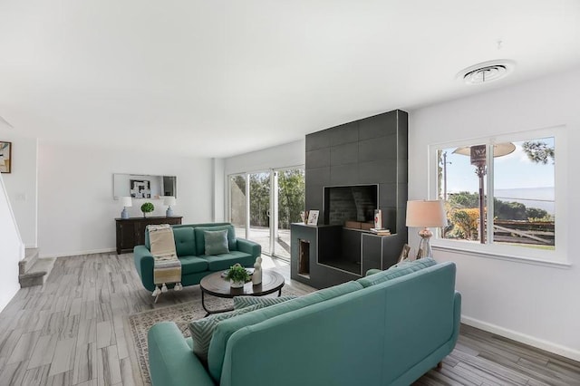 living room with a tile fireplace and light hardwood / wood-style floors