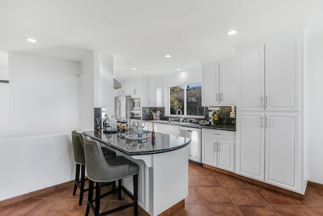 kitchen featuring kitchen peninsula, stainless steel appliances, white cabinetry, and a breakfast bar