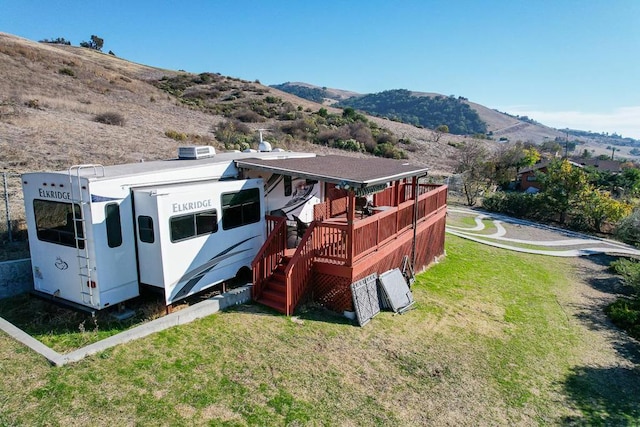 back of house with a lawn and a deck with mountain view