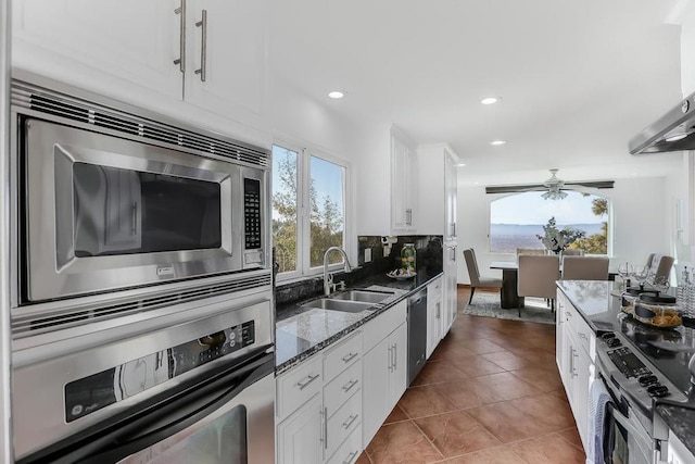 kitchen with white cabinetry, stainless steel appliances, decorative backsplash, dark tile patterned flooring, and sink