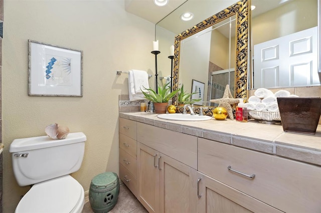 bathroom with tile patterned flooring, vanity, toilet, and walk in shower