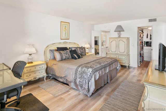 bedroom with a walk in closet, a closet, and light hardwood / wood-style floors