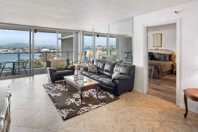 living room with a water view, floor to ceiling windows, and light tile patterned flooring