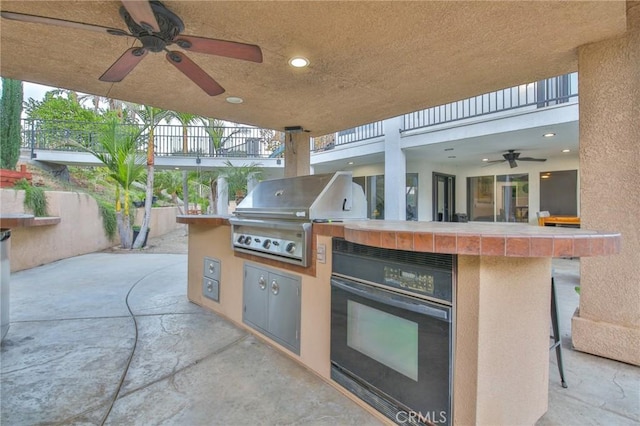 view of patio with grilling area, ceiling fan, and an outdoor kitchen