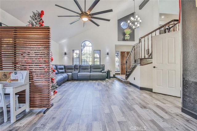 living room featuring high vaulted ceiling, ceiling fan with notable chandelier, and hardwood / wood-style flooring