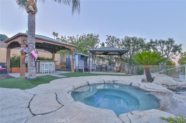 view of swimming pool with a bar, a shed, a gazebo, and an in ground hot tub