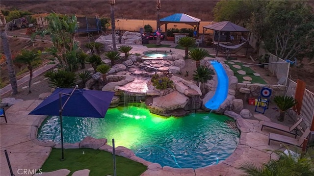 view of swimming pool featuring a trampoline, a gazebo, and a water slide