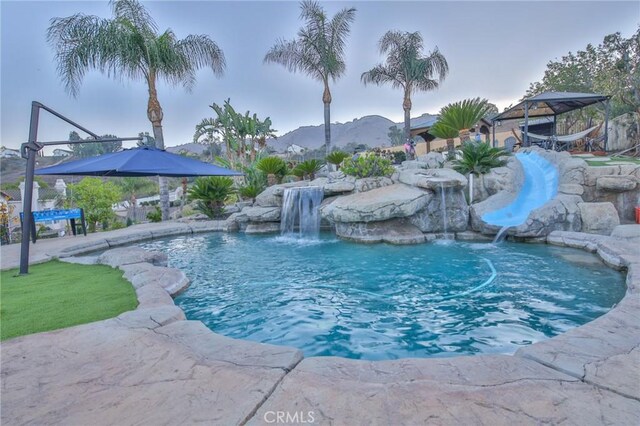 view of swimming pool with pool water feature and a mountain view