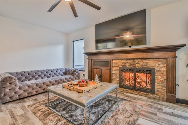 living room featuring hardwood / wood-style flooring, ceiling fan, and a fireplace