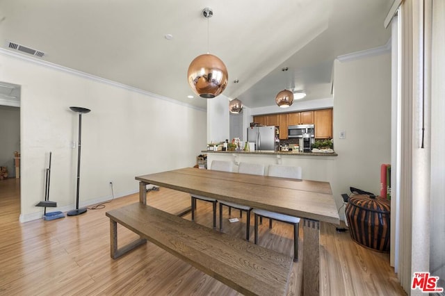 dining space featuring ornamental molding, light hardwood / wood-style flooring, and vaulted ceiling