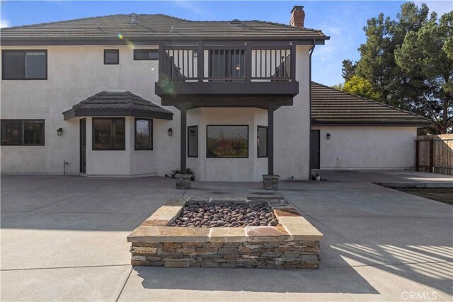 back of property featuring a balcony, a patio, and an outdoor fire pit