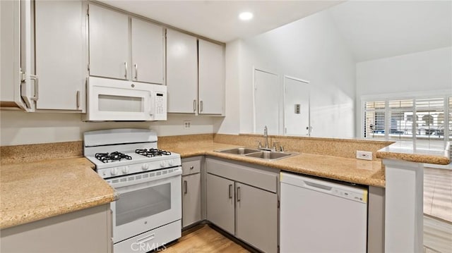 kitchen with sink, white appliances, kitchen peninsula, and light wood-type flooring