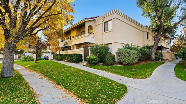 view of side of home with a yard and a balcony